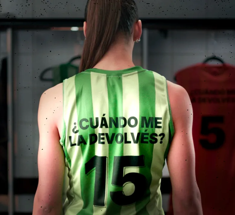 De espaldas, una chica con camiseta verde número 15 que dice ¿CUÁNDO ME LA DEVOLVÉS?